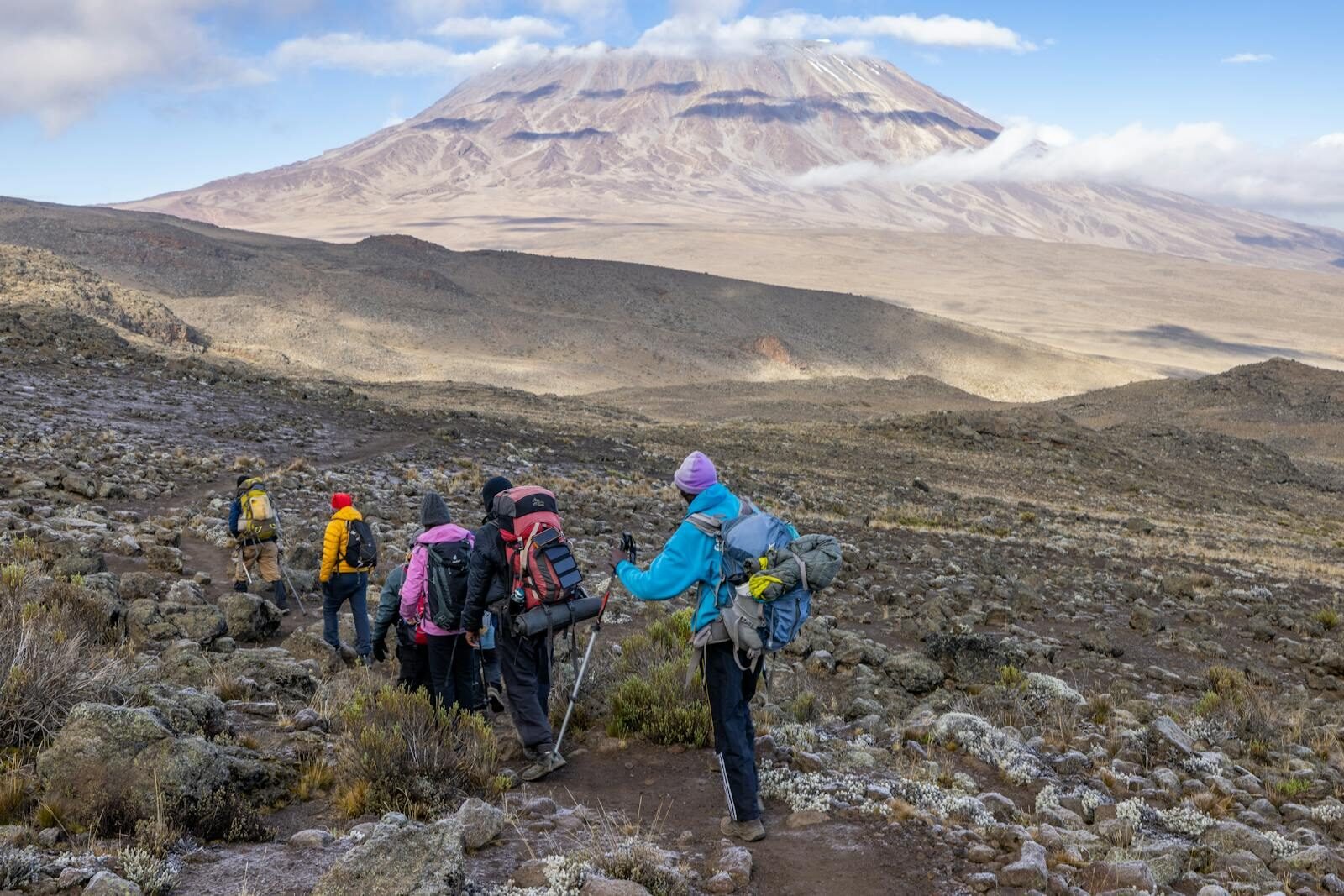 Hikers exploring the rugged trails of Mount Kilimanjaro, Tanzania, surrounded by stunning vistas. Kili Transfers